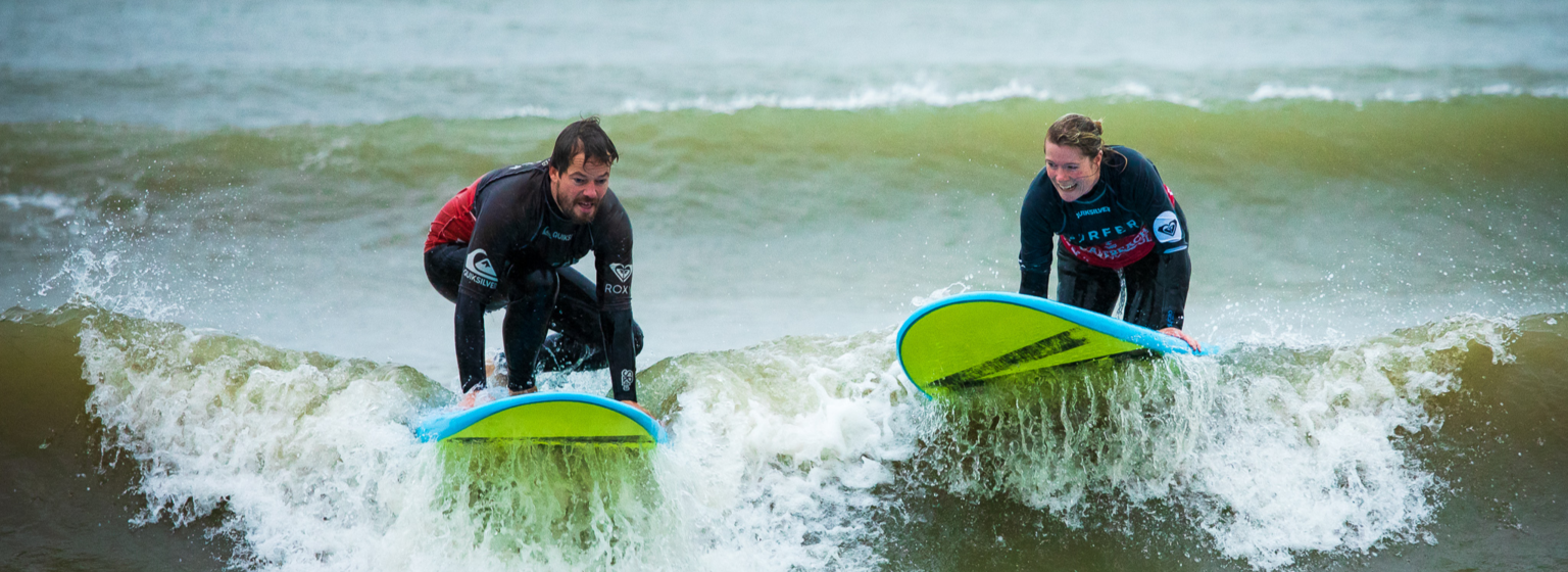 Front-end developers Anke en Sebastiaan pakken een golf op hun surfboard