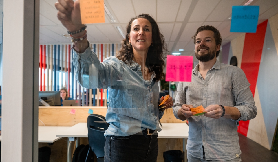 Daisy en Sebastiaan plakken post-its tijdens overleg